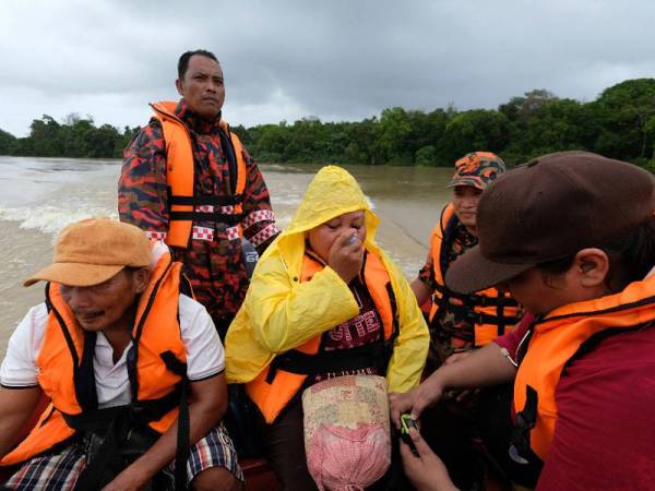 Darina ketika diselamatkan oleh anggota bomba di Kampung Mentelong hari ini.  - Foto Bernama