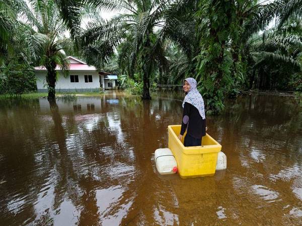 Penduduk Kampung Kasim Aaisyah Jamil,14, kelihatan bermain air di hadapan rumahnya yang masih ditenggelami air bah pada tinjauan hari ini. - Foto Bernama