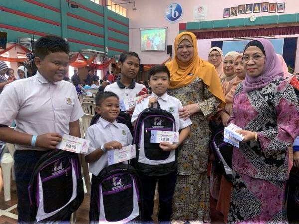 Rina (dua dari kanan) menyerahkan sumbangan Back to School 2020@KPLB Yayasan Pelajaran Mara (YPM) kepada pelajar Sekolah Jenis Kebangsaan Cina (SJKC) Gau San, Putera Muhammad Afiq Fauzul Azmi, 12, (tengah) di MRSM Tun Dr Ismail, di sini hari ini. - Foto Bernama