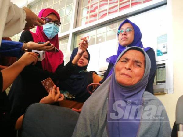 Ibu mangsa, Fatimah Bakar (duduk) tidak dapat menahan sebak.