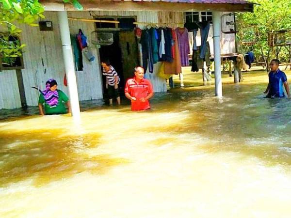 Siti Zaibah (kiri) membuat pemantauan di hadapan rumahnya sebagai persediaan awal sebelum berpindah.