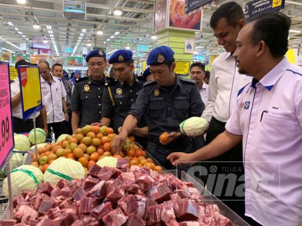 Adnan (kanan) meninjau barangan yang dijual di Mydin Kubang Kerian selepas merasmikan Skim Harga Maksimum Musim Perayaan Krismas (SHMMP) hari ini.