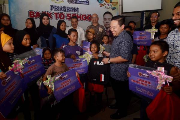 Wan Saiful beramah mesra bersama penerima bantuan beg dan peralatan persekolahan pada Program Kembali Ke Sekolah PTPTN di Sekolah Kebangsaan Bagan Jermal malam ini. -Foto Bernama