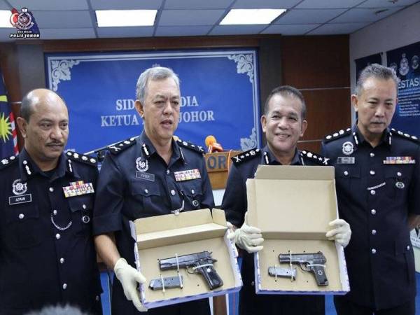 Shafie (dua, dari kanan) menunjukkan pistol yang ditemui bersama suspek selepas kejadian tembak menembak di Mersing malam semalam.- Foto Ihsan Polis Johor