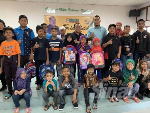 Muhamad Said (berdiri, tengah) bersama sebahagian penerima bantuan Program Jom Ke Sekolah di Dewan PPK Kluang semalam.