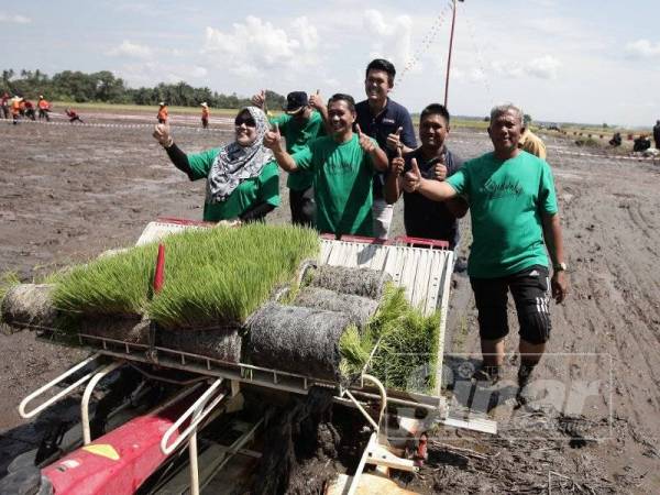 Mazlan (dua dari kiri) cuba mengendalikan mesin penanaman padi sempena Karnival Pesawah Padi@Pasir Panjang di Sekinchan, Selangor semalam.