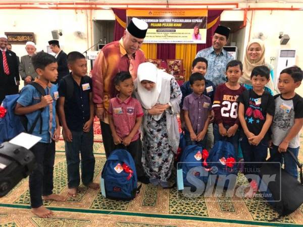 Tengku Muhammad Rizam (tiga dari kiri) bersama Tunku Noor Hayati (lima dari kiri) bermesra dengan murid terpilih yang menerima bantuan peralatan sekolah daripada Maik.