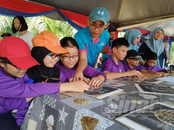 Amer (tengah, berdiri) memberi penerangan tentang gerhana matahari anulus kepada murid masalah penglihatan di Taman Negara Johor Tanjung Piai.