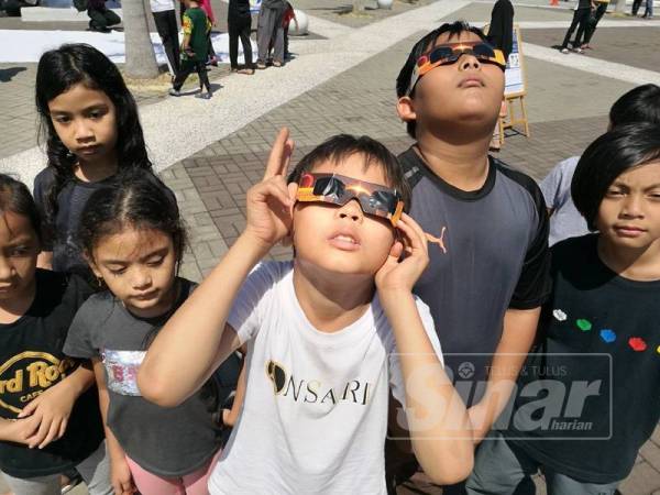 Muhammad Hamizan (dua dari kanan) bersama Wan Haziq Haidar melihat gerhana matahari anulus di PSKT di sini hari ini.