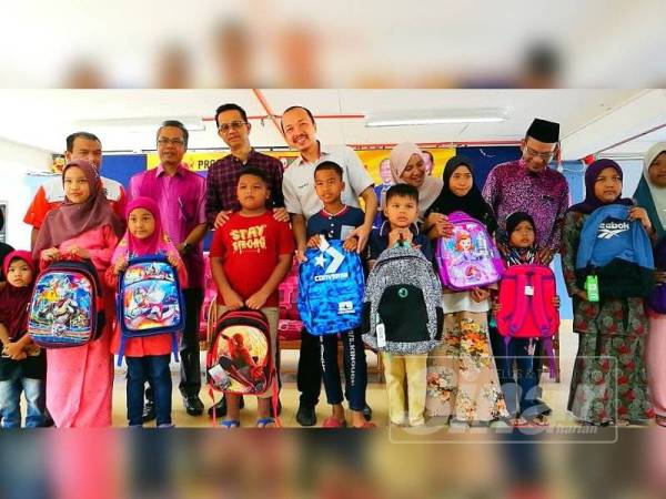 Mohd Hisyamuddin (belakang, empat dari kiri) bersama penerima kelengkapan sekolah sempena Program Jom Ke Sekolah di Pasir Mas semalam.