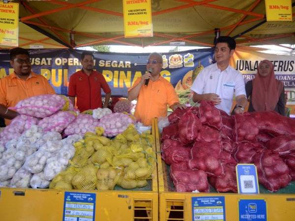 Pengerusi LKIM, Muhammad Faiz Fadzil (dua dari kanan) bersama Ishak menjual bawang di bawah harga pasaran pada Program Bazar Peduli Rakyat di Kampung Pelet hari ini. - Foto Bernama