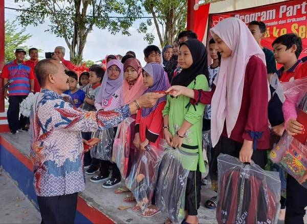 Abu Bakar menyerahkan sumbangan kepada salah seorang anak fakir miskin sempena Program Kembali Ke Sekolah dan Agihan Bantua di Sungai Abong, Muar, Johor semalam.