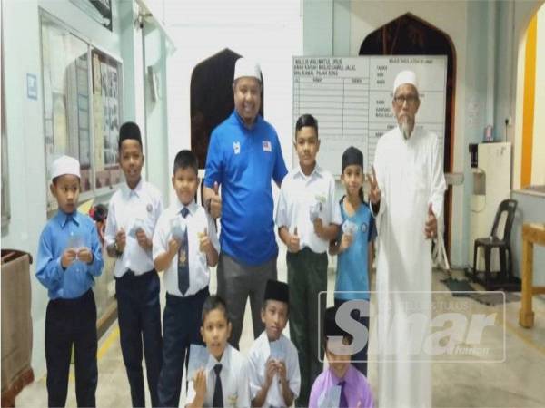 Khairol Fitri (tengah) bergambar bersama pelajar yang menerima wang saku selepas hadir solat Subuh berjemaah di masjid pagi tadi.