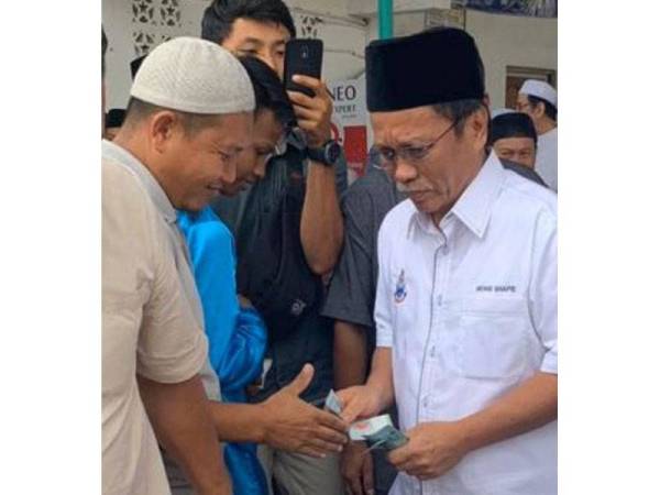 Foto Shafie menghulurkan wang kepada orang ramai yang menjadi tular di laman sosial sejak semalam.