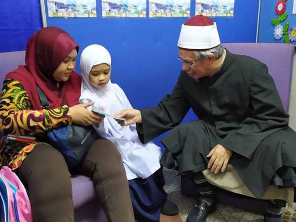 Zulkifli menyampaikan sumbangan kepada Nur Khairunnisa yang ditemani ibunya. - Foto Twitter Dr Zulkifli Mohamad al-Bakri