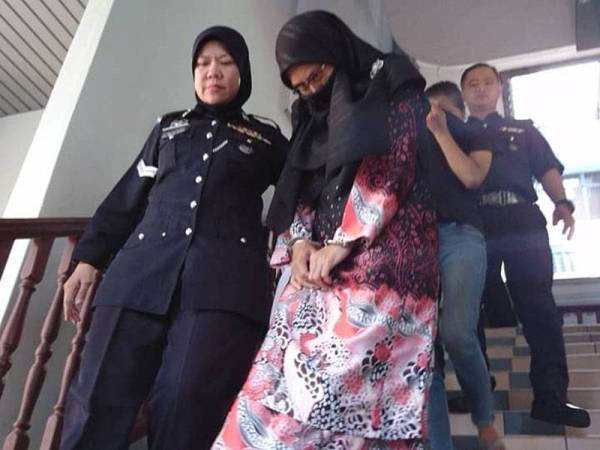 Haslina (bertudung hitam) ketika di bawa keluar dari Mahkamah Majisret Ayer Keroh di sini, hari ini, atas pertuduhan menyembunyikan dan mengalihkan harta melalui akaun bank.