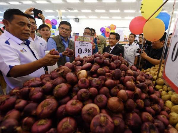 Saifuddin Nasution (tiga, kiri) menunjukkan bawang merah dijual dengan harga murah di Pasar Raya TF Value-Mart cawangan Balik Pulau selepas merasmikan pasaraya syarikat TF Value-Mart Sdn Bhd hari ini. - Foto Bernama