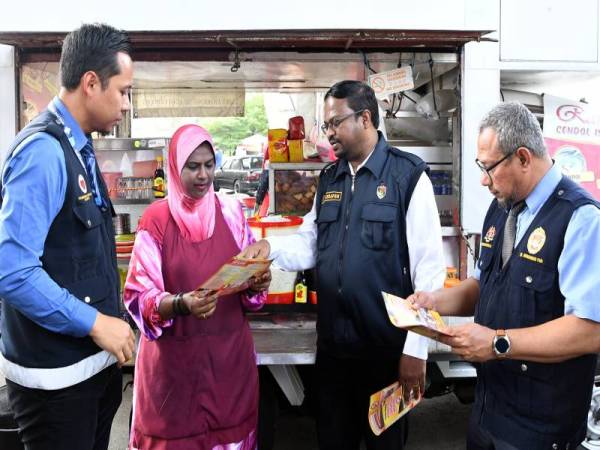 Veerapan (dua dari kanan) menerangkan kepada pengusaha makanan van bergerak, Khatijah Abdul Radzak (dua dari kiri) mengenai tempat-tempat yang dikuatkuasakan larangan merokok pada Operasi Penguatkuasaan Larangan Merokok di Tempat Makan, hari ini. - Foto Bernama