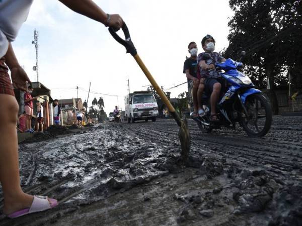 Penduduk menggunakan penyodok untuk membersihkan lumpur dan debu tebal dibebaskan Taal yang meliputi jalan sekitar bandar Tanauan di wilayah Batangas. - Foto AFP