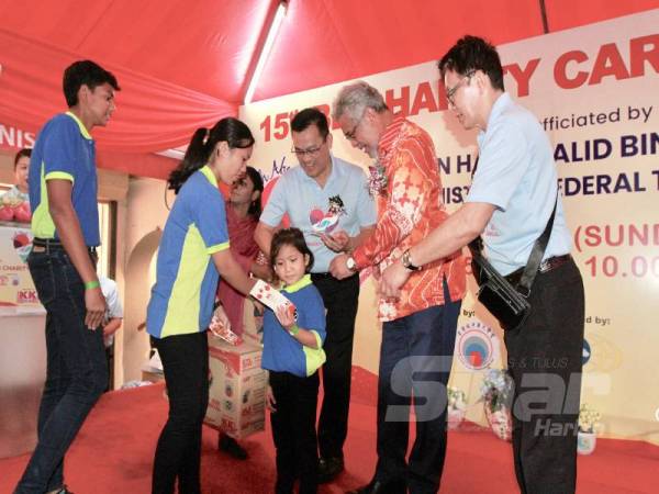 Khalid bersama KK Chai menyampaikan sumbangan kelengkapan harian berserta angpau kepada penerima sumbangan di Karnival BB Charity di Kuala Lumpur. - FOTO ZAHID IZZANI
