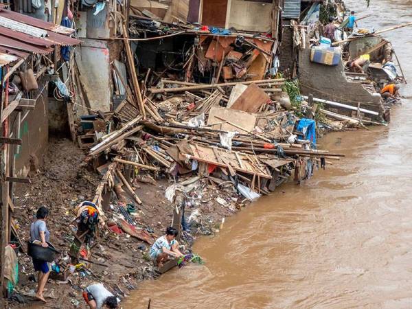 Penduduk membersihkan rumah mereka selepas banjir dicetuskan hujan lebat melanda Jakarta pada 1 Januari lalu. - Foto AFP