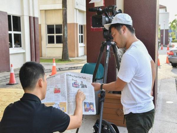 Krew Asahi TV dari Jepun melihat berita kemalangan Kento Momota yang disiarkan surat khabar tempatan semasa membuat liputan perkembangan pemain badminton nombor satu dunia itu di Hospital Putrajaya hari ini. - Foto Bernama