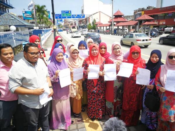 Shahaniza (tengah) menunjukkan laporan polis yang telah dibuat di IPD Kuantan.