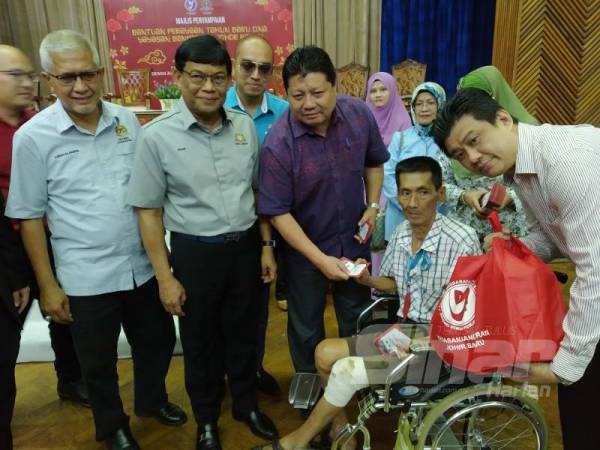 Mazlan ( tiga dari kanan) menyampaikan sumbangan Yayasan Majlis Bandaraya Johor Bahru sempena Tahun Baru Cina kepada salah seorang penerima di Dewan Jubli Intan Majlis Bandaraya Johor Bahru hari ini.