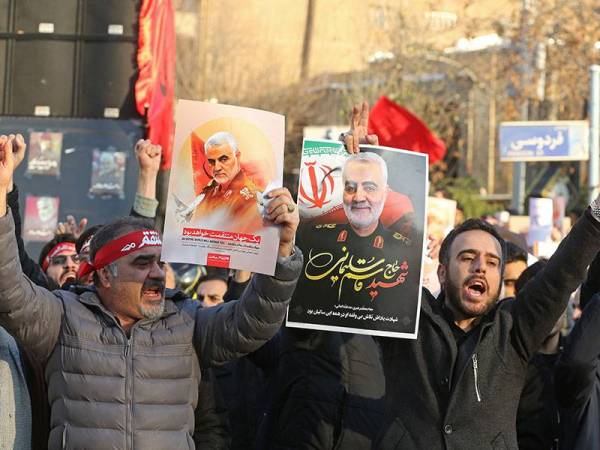 Penunjuk perasaan Iran memegang sepanduk wajah Soleimani ketika berkumpul di hadapan Kedutaan Britain di Teheran hujung minggu lalu. - Foto AFP