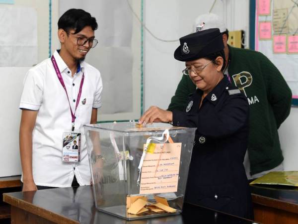 Anggota polis Koperal Dayang Gapah @ Abdullah memasukkan kertas undi sewaktu mengundi awal di Pusat Pengundian Awal di Bilik Gerakan Balai Polis Membakut pada PRK Parlimen Kimanis Selasa lalu. - Foto Bernama