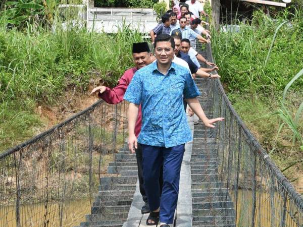 Mohamed Azmin Ali meniti jambatan gantung ketika berkunjung ke rumah Suriyani Sharoni untuk Santai Mesra bersama rakyat di Kampung Baitam Baru dekat sini hari ini. -Foto Bernama