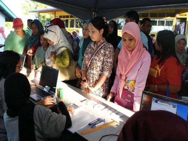 Orang ramai beratur untuk menyemak senarai saluran dan nama untuk mengundi bagi PRK Kimanis di SK Kimanis dekat sini hari ini.- Foto Bernama