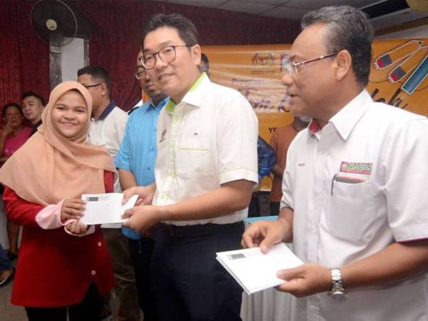 Abu Sujak (kanan) mengiringi Tze Tzin (dua dari kanan) menyerahkan baucar bernilai RM200 kepada pelajar sempena program Back To School di Dewan Persatuan Penduduk Bayan Baru, Pulau Pinang semalam.