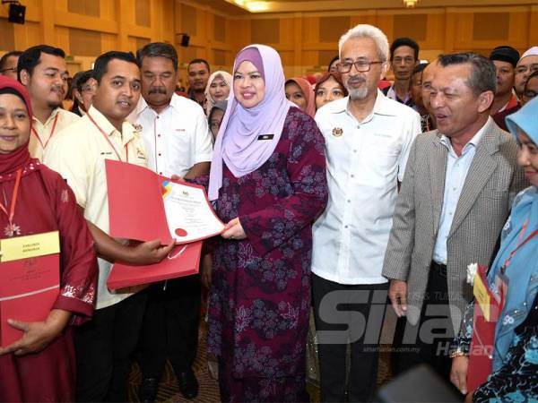 Rina (tengah) menyampaikan watikah pelantikan MPKKP peringkat Terengganu di Kuala Terengganu.