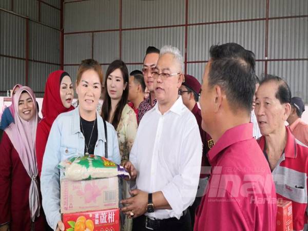 Noh (dua dari kanan) menyampaikan sumbangan sempena Tahun Baru Cina di Dewan Terbuka MCA Pekan Tanjong Karang di sini hari ini.