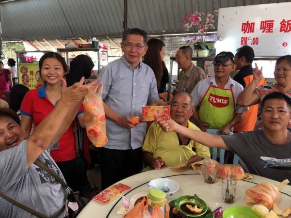 Salahuddin (tengah) mengagihkan sampul angpau serta limau mandarin kepada penduduk ketika turun padang melawat kawasan DUN Simpang Jeram sempena sambutan Tahun Baru Cina di Pasar Baru Sakeh hari ini. -Foto Bernama