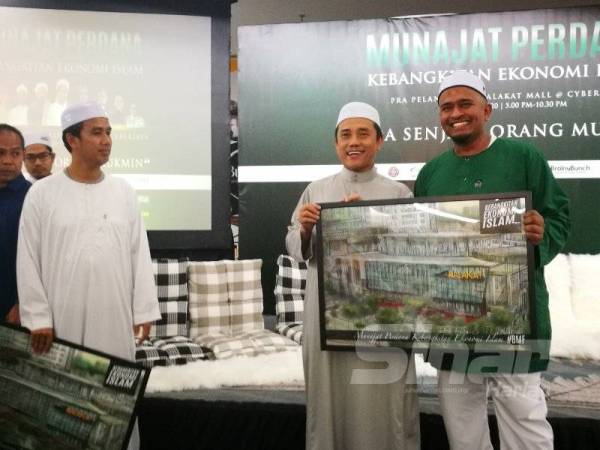 Fadzil (kanan) menyampaikan cenderahati kepada Presiden Pembela, Aminuddin Yahaya yang turut hadir pada Pra Pelancaran Malakat Mall Cyberjaya di sini malam tadi.