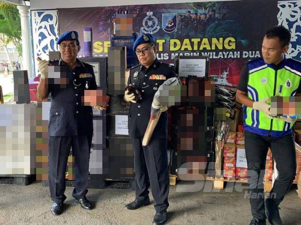 Abdul Rahman (dua dari kiri) menunjukkan minuman keras yang dirampas dalam serbuan berasingan.