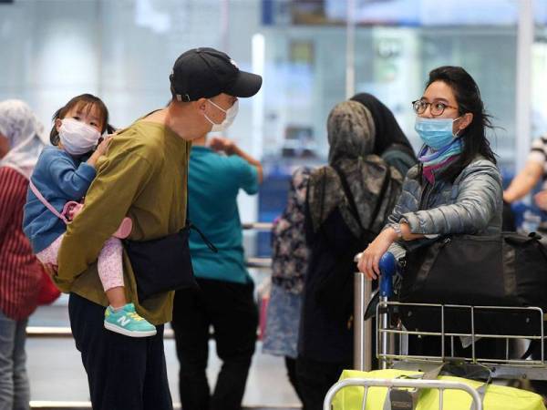 Kelihatan sebuah keluarga memakai topeng penutup mulut dan hidung ketika tinjauan di Lapangan Terbang Antarabangsa Kuala Lumpur (KLIA), hari ini.-fotoBERNAMA