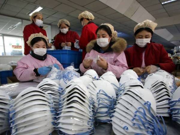 Pekerja membungkus topeng muka di sebuah kilang di Handan, China. - Foto Agensi