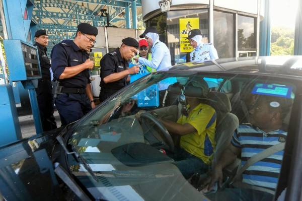 Arjunaidi Mohamed (tiga, kiri) menyampaikan cenderahati kepada pengguna jalan raya pada Program Advokasi Op Selamat 16 sempena Tahun Baru Cina Peringkat Kontinjen Selangor di Plaza Tol Gombak hari ini. -Foto Bernama