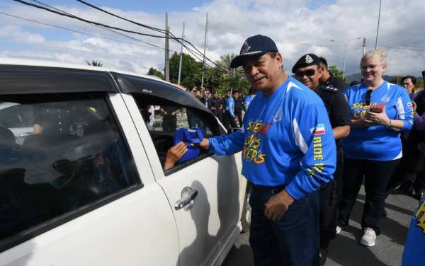 Omar mengedarkan cenderahati berupa risalah kepada para pengguna jalan raya sempena Kempen Bermotosikal, Kembara Memerangi Dadah dan Pencegahan Jenayah serta´Op Selamat 16' bersama Pesuruhjaya Polis Sabah hari ini. - Foto: Bernama
