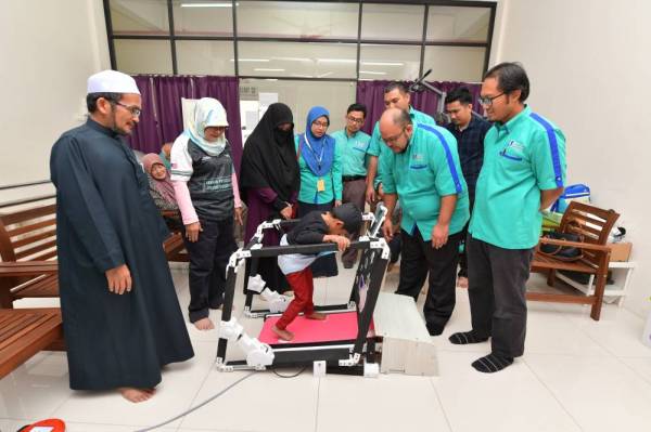 Dr Mohd Azrul Hisham membantu pesakit kanak-kanak menggunakan PhyMill sambil diperhatikan pakar fisioterapi, Narimah Daud (dua dari kiri) semasa serahan peralatan ini untuk kegunaan pihak Kuantan Physical Therapy-Physiotherapy Center Kuantan baru-baru ini.