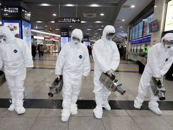 Kakitangan kesihatan Korea Selatan menyembur penyahjangkit di bas terminal bas Gwangju sebagai usaha membendung penularan koronavirus. - Foto AFP