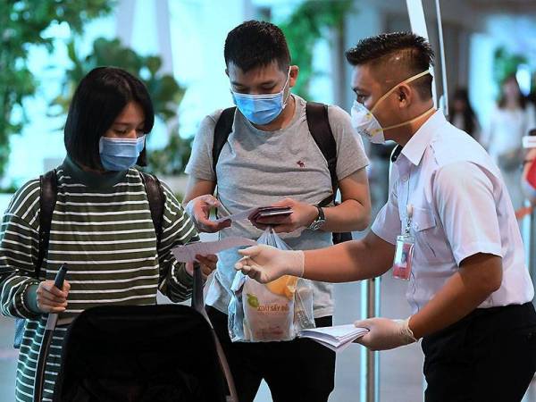 Seorang kakitangan mengedarkan risalah tentang jangkitan 2019 Novel Koronavirus (2019-nCoV) kepada setiap penumpang yang baru sahaja tiba di KLIA2. -Foto Bernama