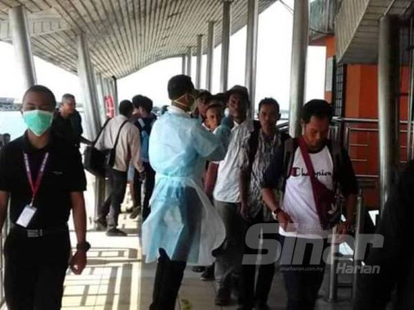 Penumpang feri menjalani pemeriksaan suhu badan di Terminal Feri Antarabangsa Kukup.