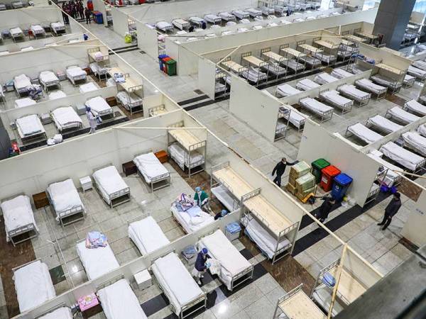 Kakitangan perubatan menyediakan katil untuk menerima pesakit menunjukkan simptom sederhana koronavirus di pusat pameran yang dijadikan pusat perubatan sementara di Wuhan. - Foto AFP