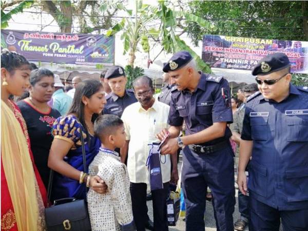 Suressh Kumar menunjukkan panduan keselamatan kepada pengunjung sempena program High Profile Policing di Kuil Sri Subramaniar, Gunung Cheroh hari ini.