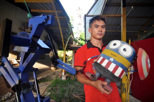 Kevin menunjukkan arca animasi Minions yang dihasilkan di bengkelnya di Kampung Tambalugu, Tuaran dan dijual pada harga RM60. -Foto Bernama