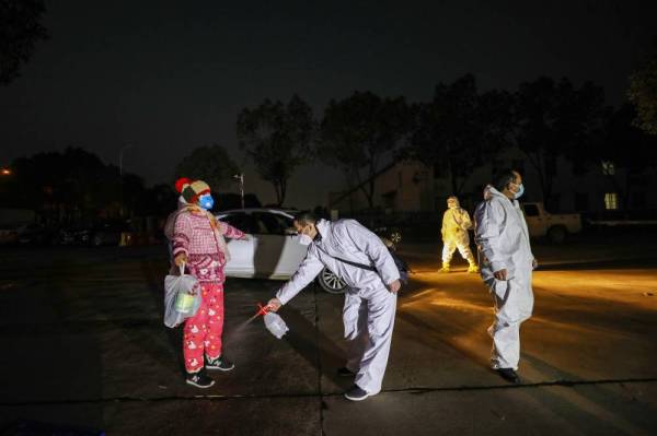 Semburan nyahjangkit dilakukan terhadap pesakit yang kembali dari hospital dan memasuki zon kuarantin di Wuhan. - Foto AFP
